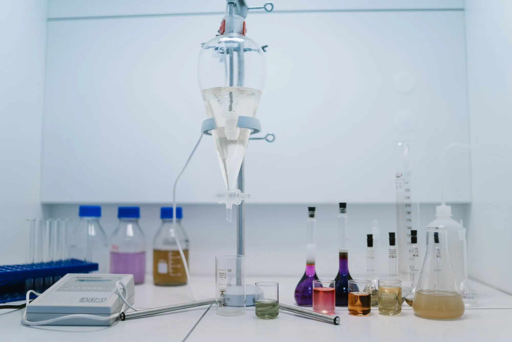 Laboratory glassware containing colored liquids on a white workbench.