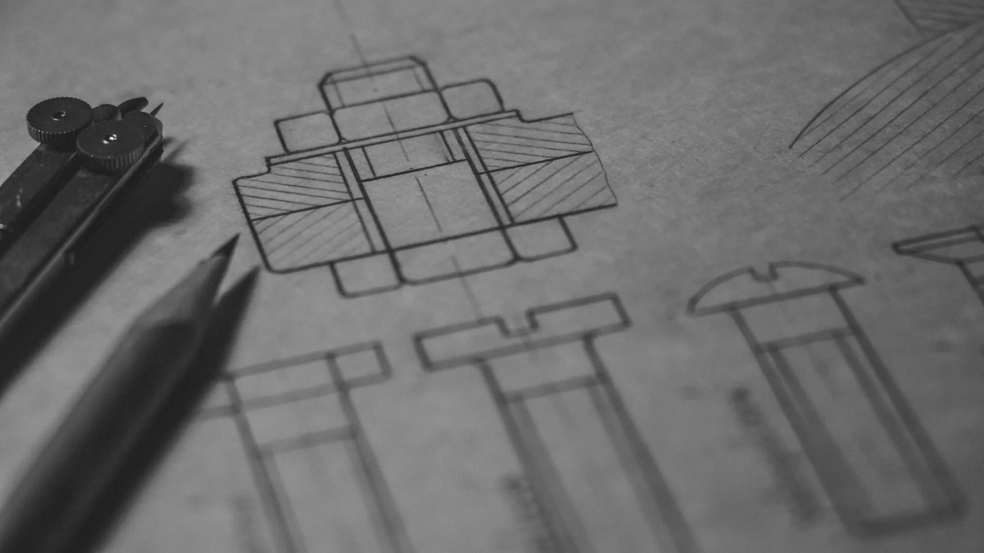 Technical drawings and drafting tools on white paper.