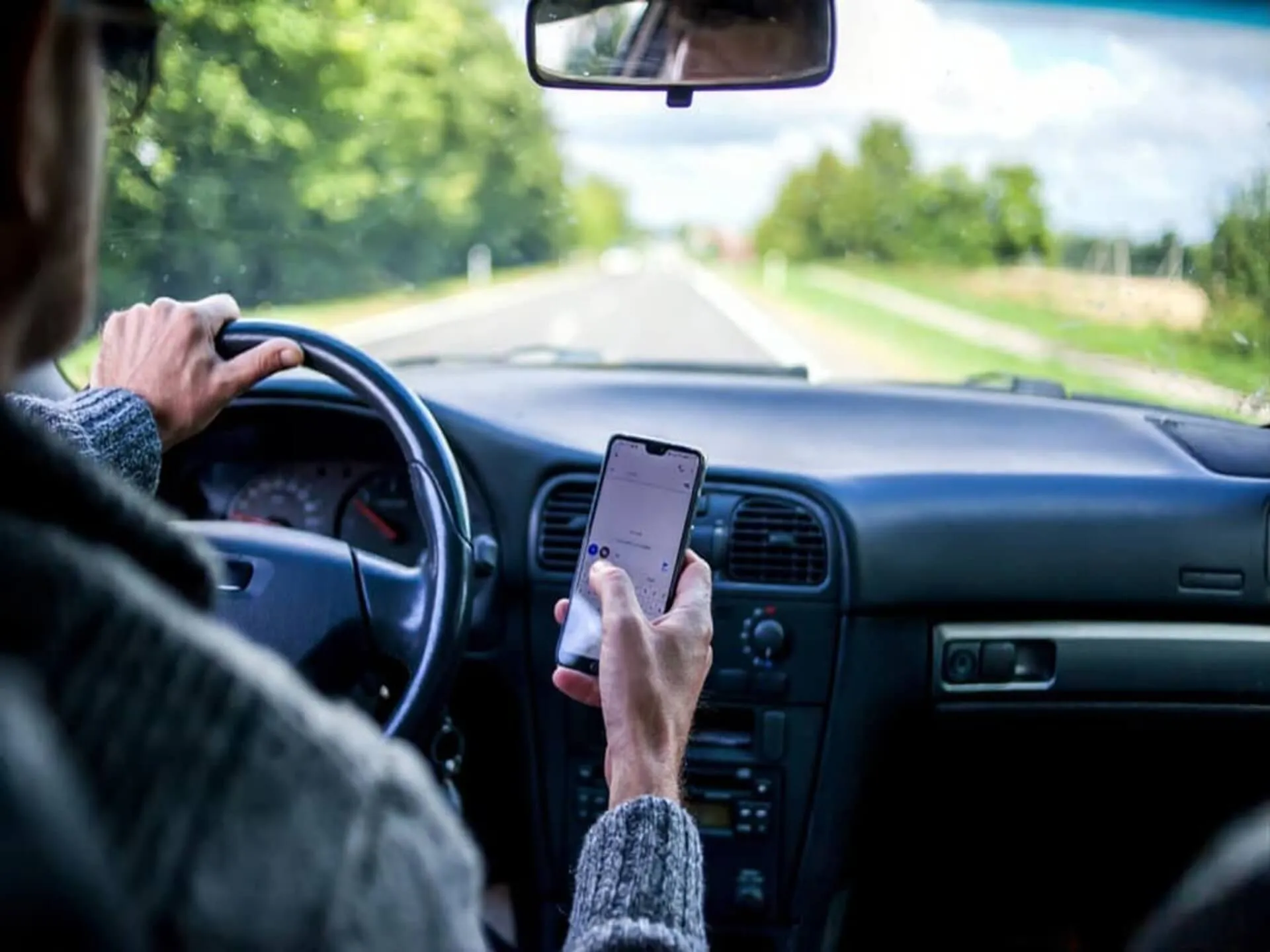 A driver holding a phone beside the steering wheel.
