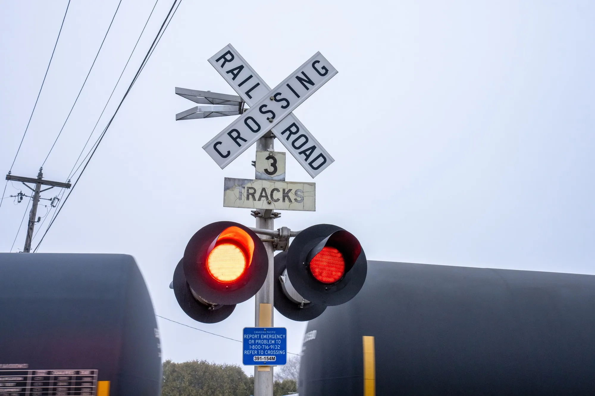Railroad crossing signals with a freight train in the background.