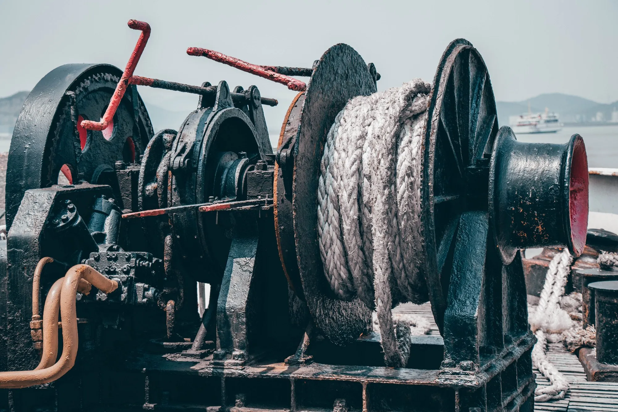 A rope wound around a metal winch on a vessel deck.