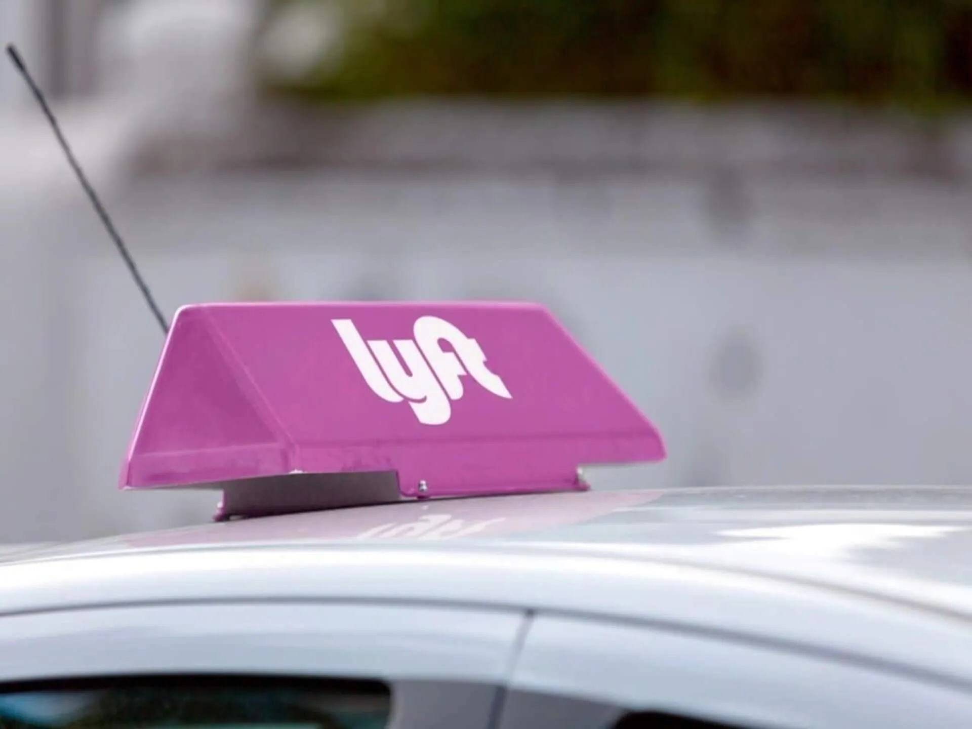 A pink Lyft sign on the roof of a vehicle.