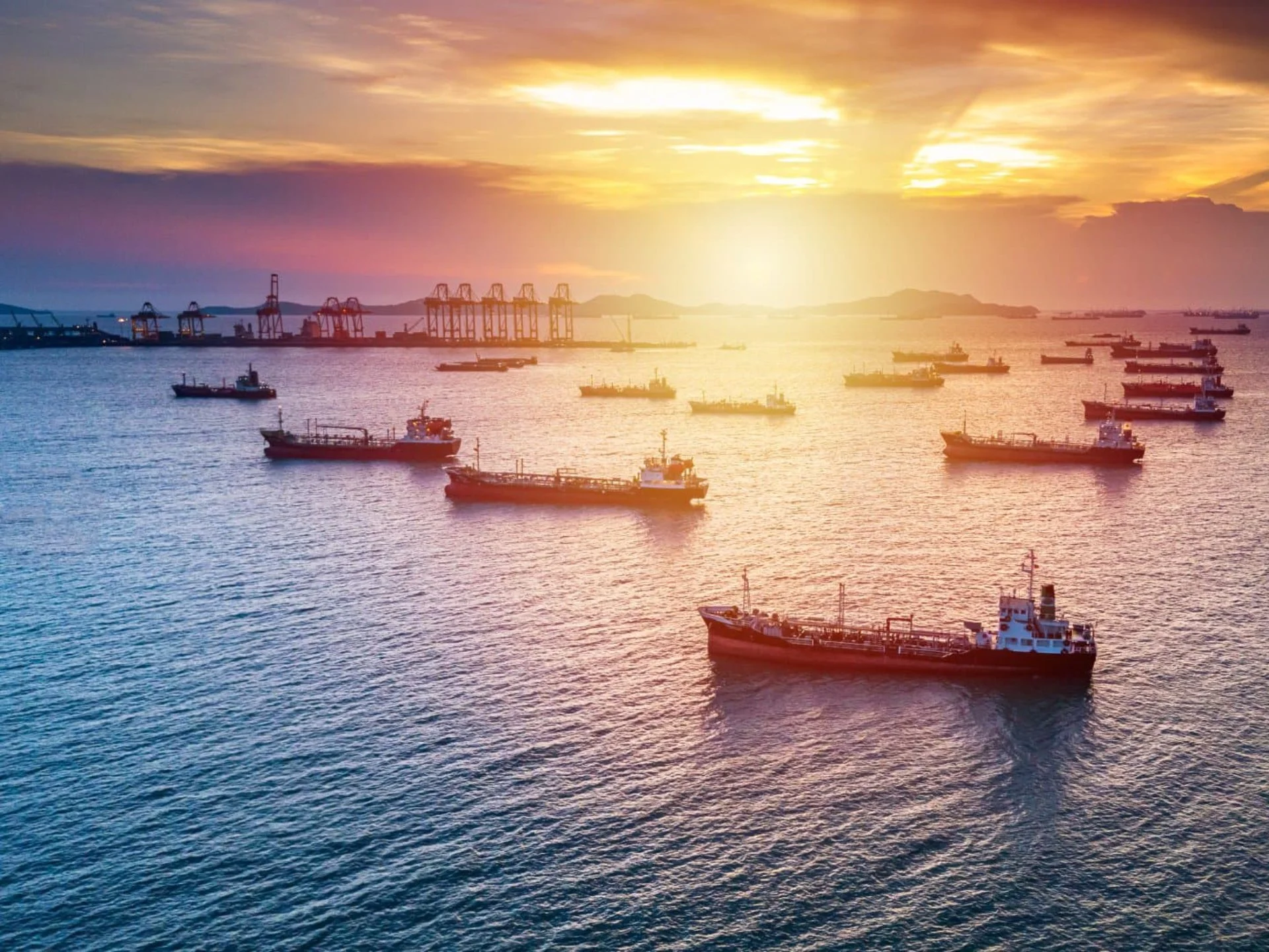 Ships on harbor water at sunset.