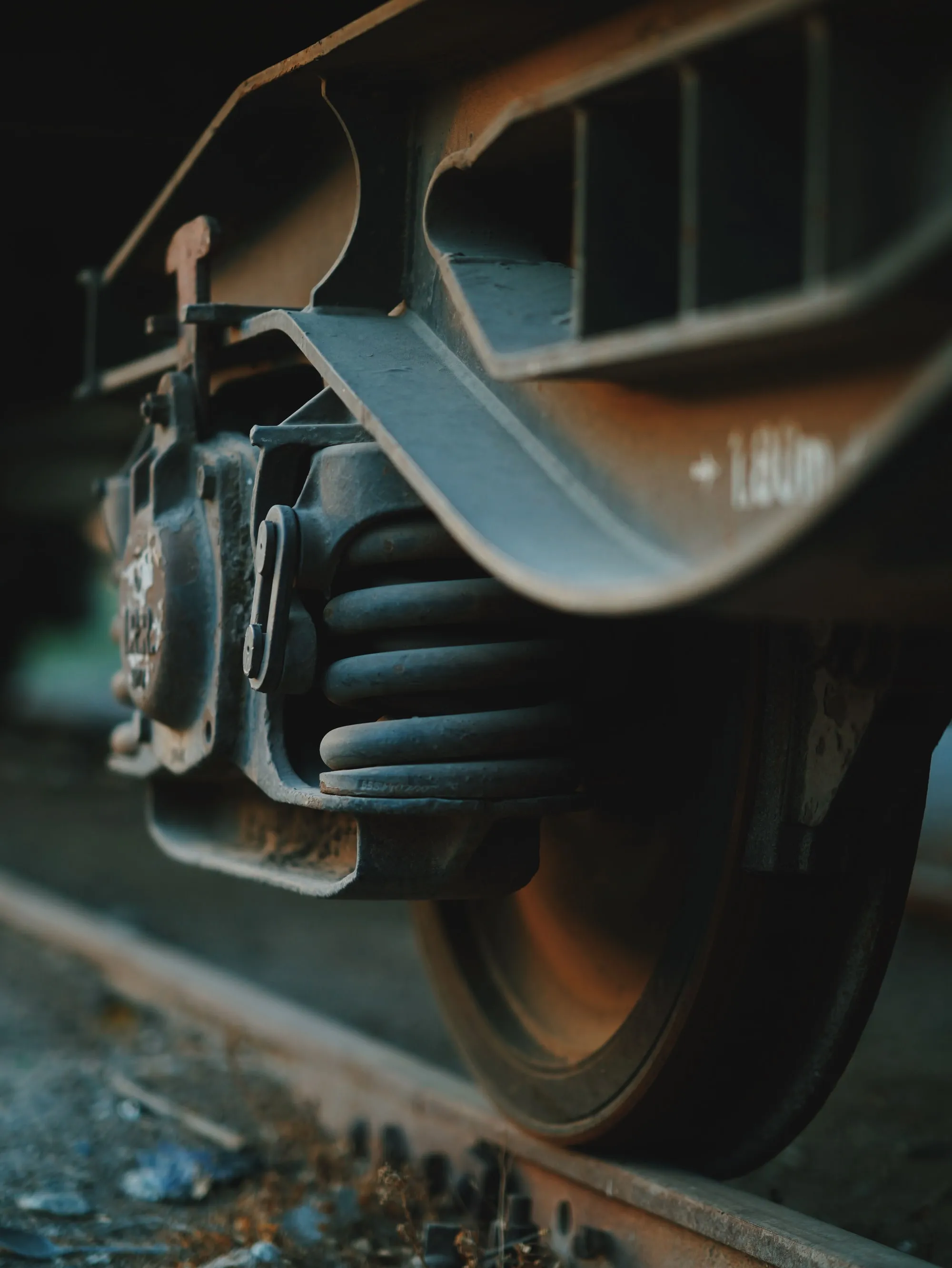 A railroad wheel and suspension springs above a rail.