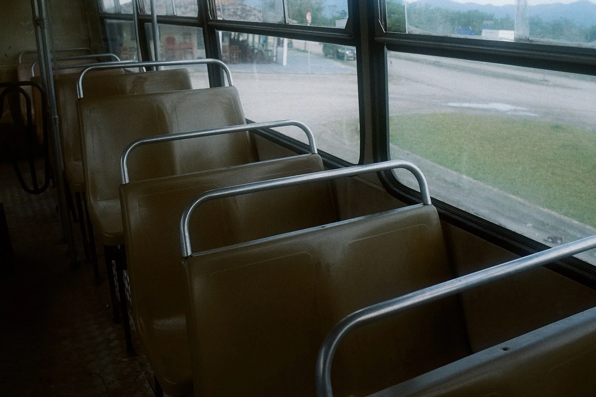 Empty passenger seats and handrails inside a bus.