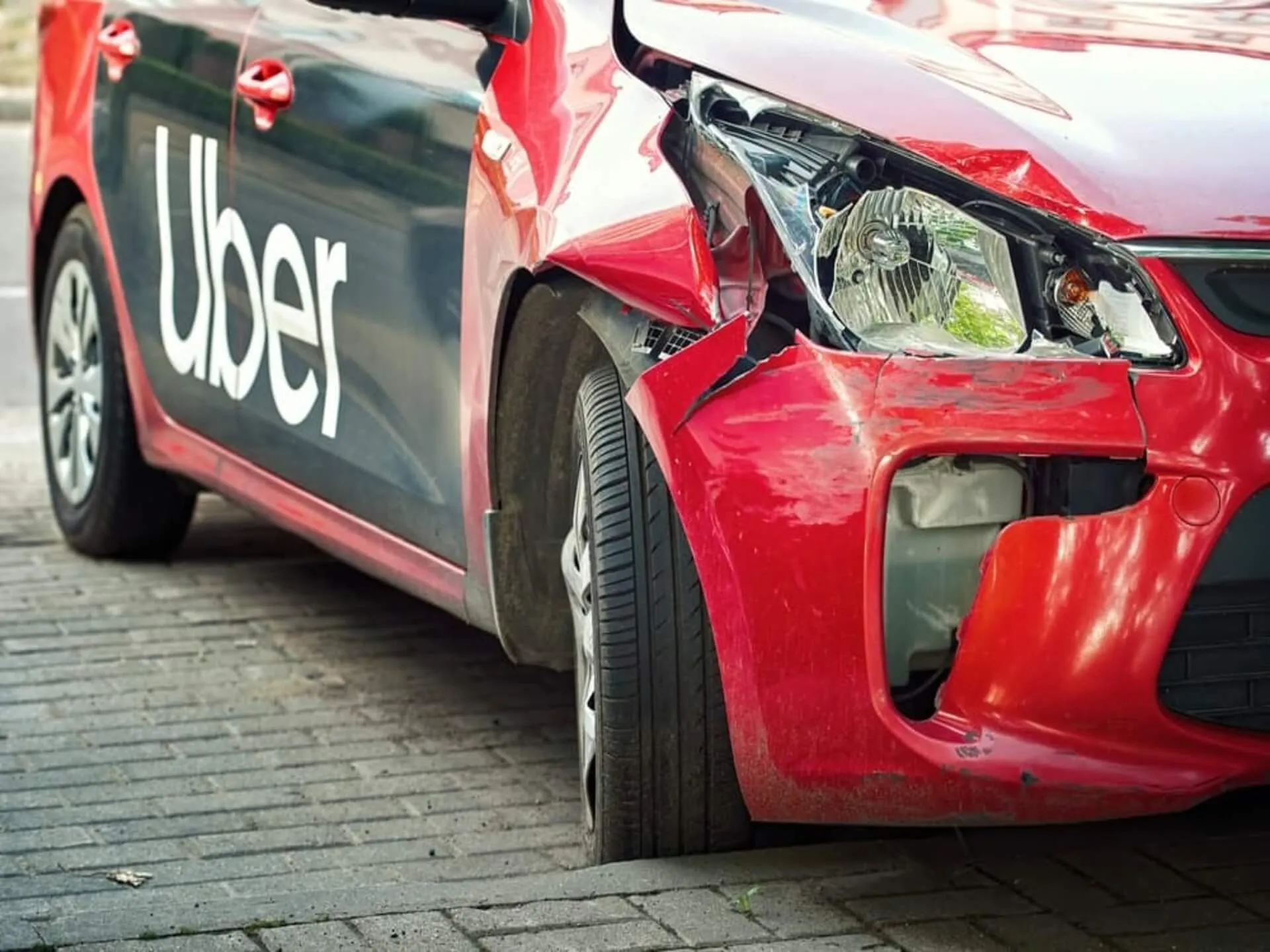 A damaged red car displaying Uber branding.