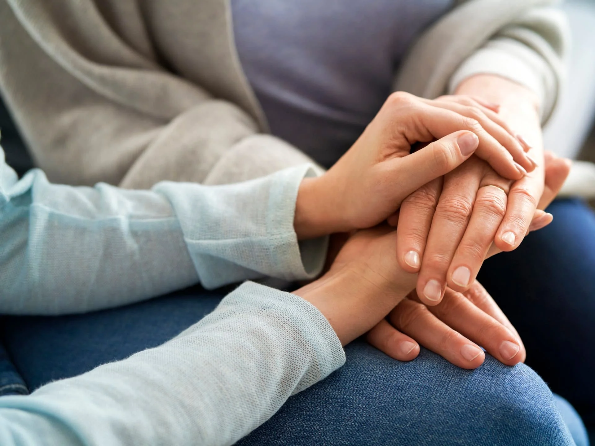 Hands resting together on a person's knee.